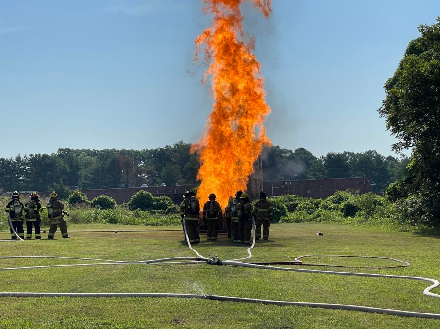 Volunteer firefighters operating on a scene with apparatus in the background